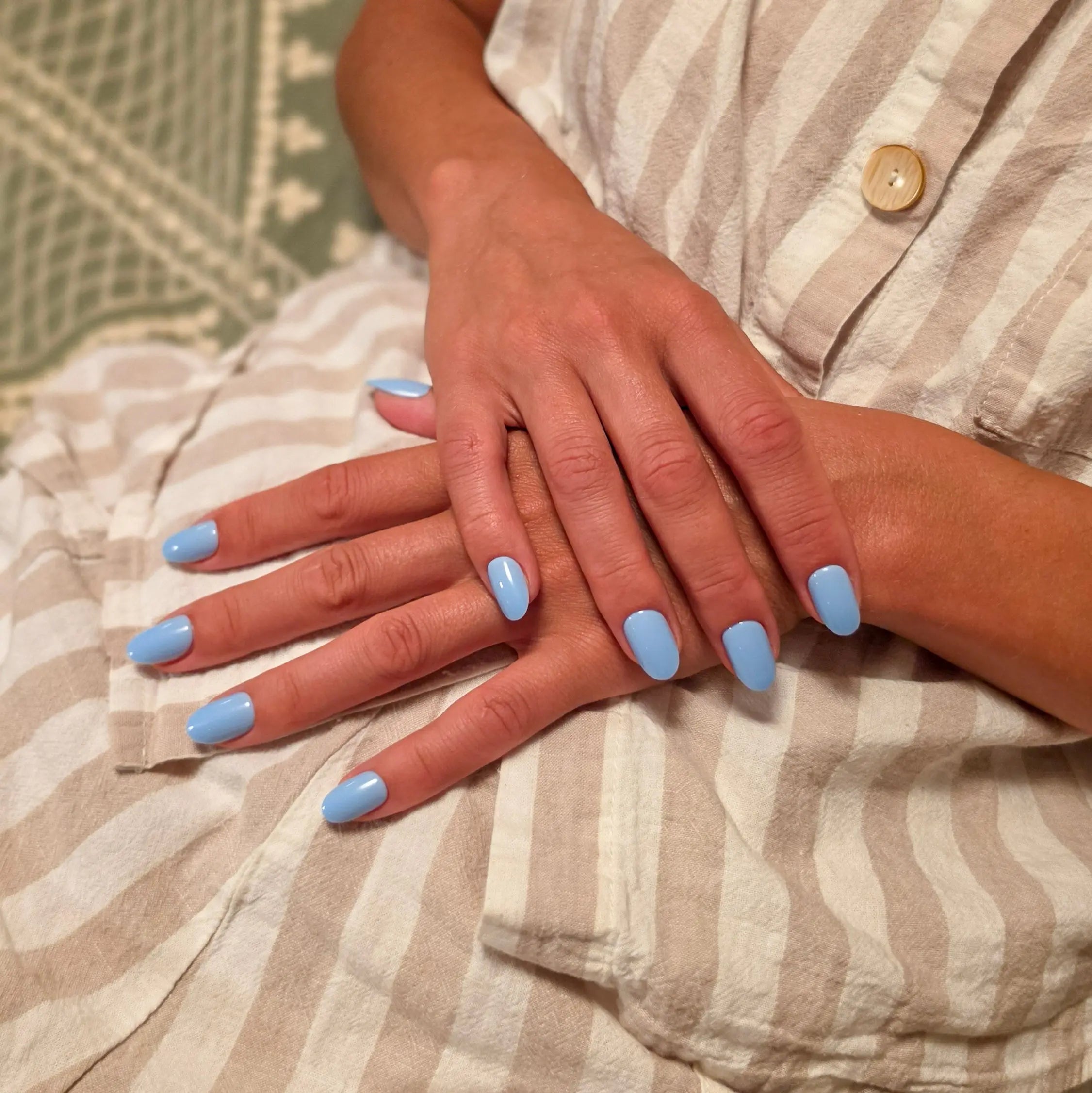 Press-on nails Bleu Ciel arrondi courts deux mains croisées sur tenue en lin rayée, LYLY Nails