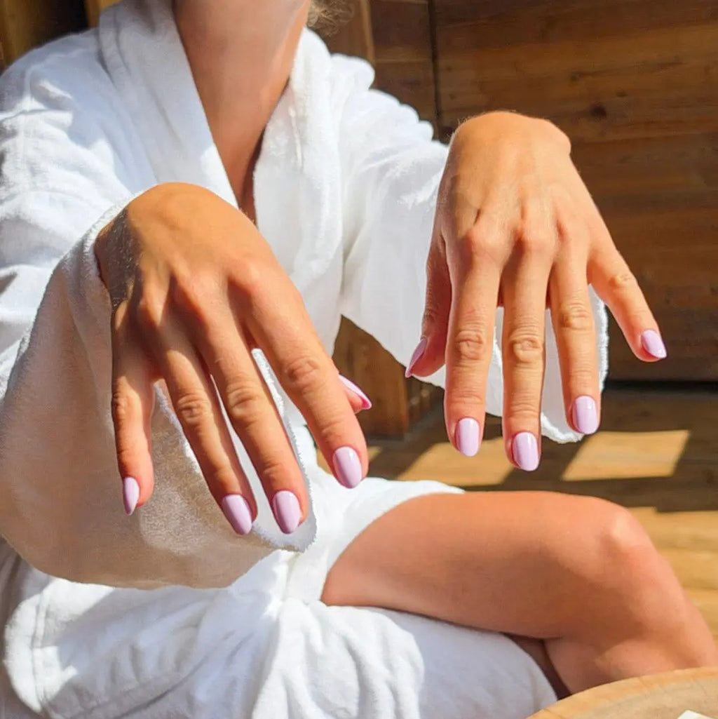  Press-on nails Rose Dragée arrondi courts deux mains en peignoir blanc à la lumière du soleil, LYLY Nails