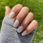 Press-on Nails Blanc Nacré carrés courts portés en extérieur, reflets nacrés sur faux ongles, pull gris et pelouse verte, manucure lumineuse et sophistiquée LYLY Nails