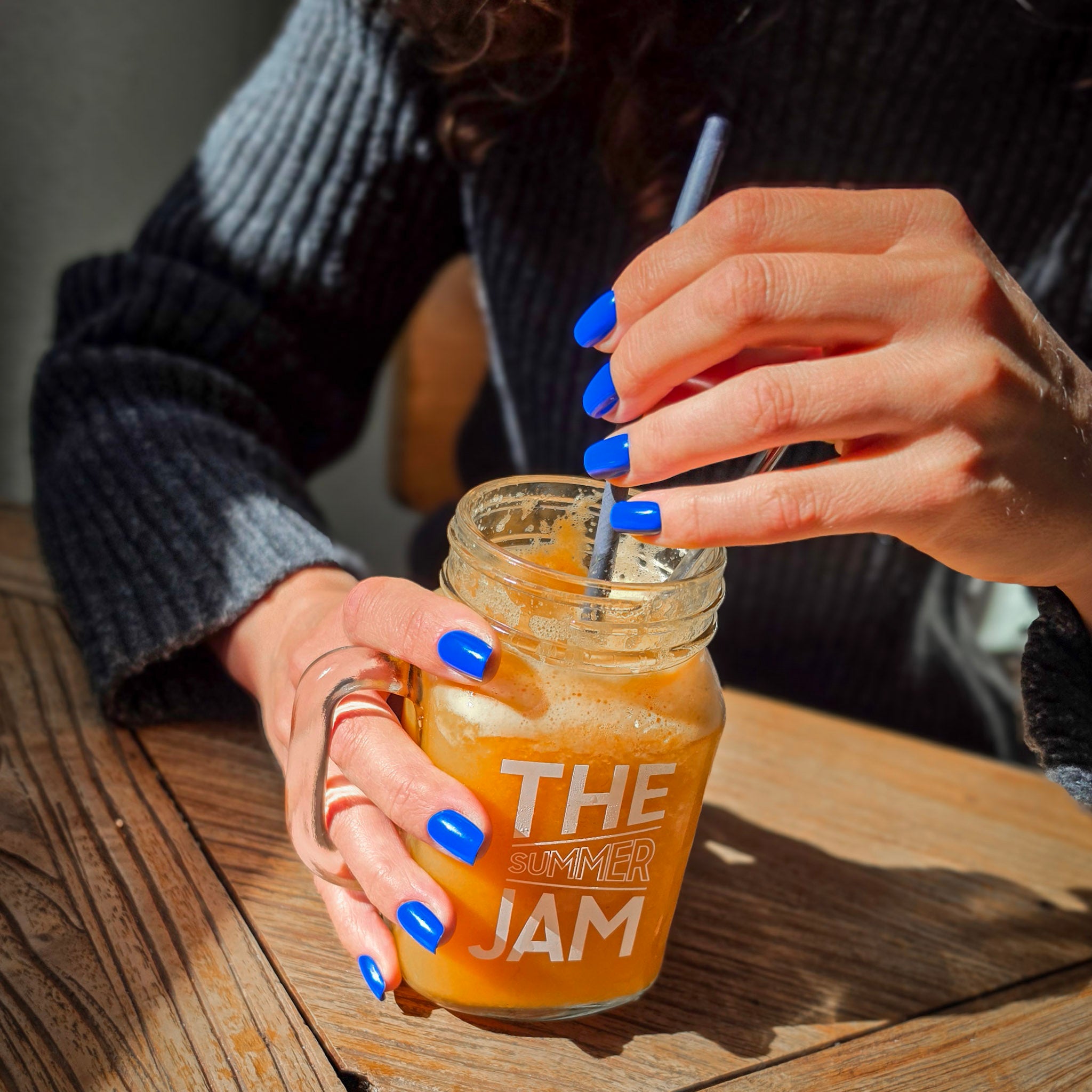 Manucure press-on Bleu Électrique carrés courts, deux mains tenant un jus de fruits en terrasse au soleil, look urbain décontracté, ongles bleu éclatants LYLY Nails