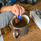 Faux ongles Bleu Électrique carré court sur main tenant un cookie au-dessus d'une tasse de thé, ambiance cosy intérieur, ongles bleus intenses et gourmands LYLY Nails