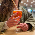 Faux ongles Corail Rosé forme carrée courte sur main tenant un cocktail, ambiance bar soirée, ongles faux corail festifs et élégants LYLY Nails