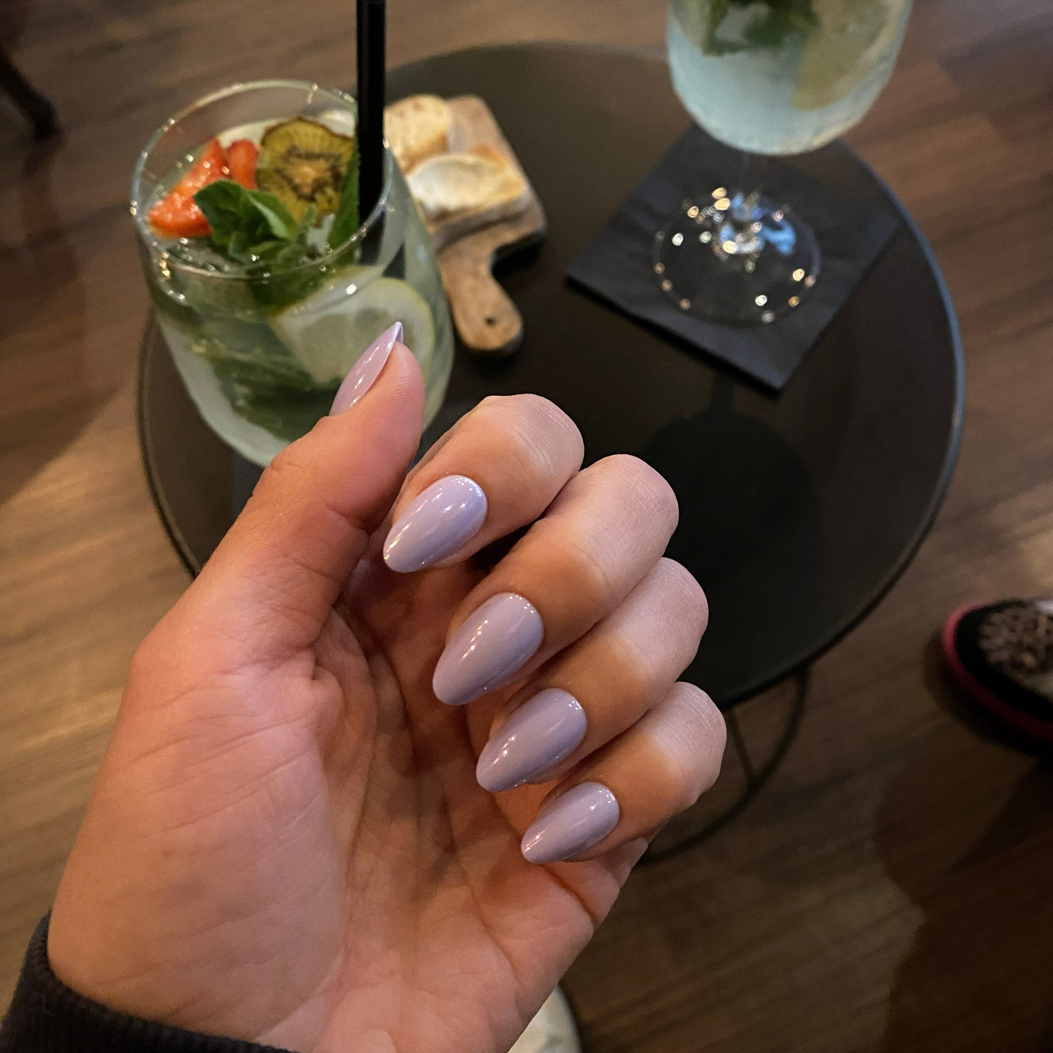 Press-on Nails Lavande Douce carrés amande courts en soirée bar, table noire et mojito en fond, faux ongles violet doux, ambiance chic et décontractée LYLY Nails