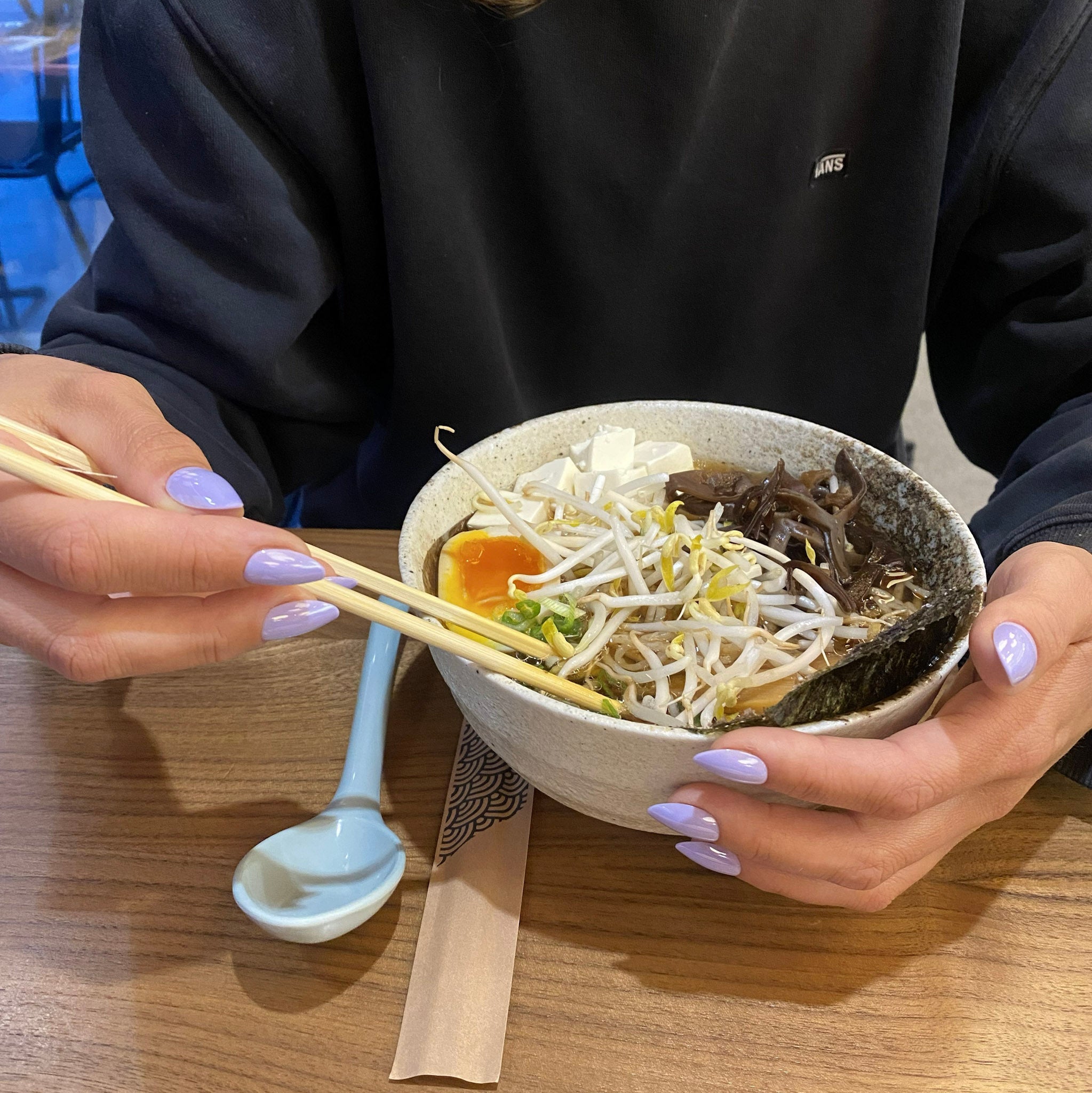 Press-on Nails Lavande Douce amande courts sur deux mains tenant un bol de ramen, ambiance restaurant japonais, faux ongles violet pastel délicat LYLY Nails