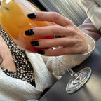 Press-on Nails Noir Intense carrés courts portés au bar, main tenant un cocktail, bague dorée, ambiance soirée élégante LYLY Nails