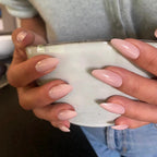 Press-on Nails Pêche Douce amande moyen sur deux mains tenant un bol blanc céramique, sweat gris et jeans, ongles nude pêche glossy LYLY Nails
