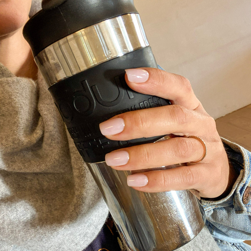 Faux ongles Rosé Doux carrés courts sur main tenant une thermos à café, look casual gris et denim, ongles roses discrets et élégants LYLY Nails