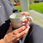 Press-on Nails Rose Lait forme arrondie courte, deux mains tenant un mug en céramique au soleil, ambiance détente outdoor, ongles naturels et lumineux LYLY Nails