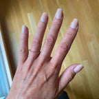 Press-on Nails Rose Nude Brillant carrés courts sur main ouverte, bague fine dorée, parquet bois en fond,faux ongles nude nacré lumineux et naturels LYLY Nails