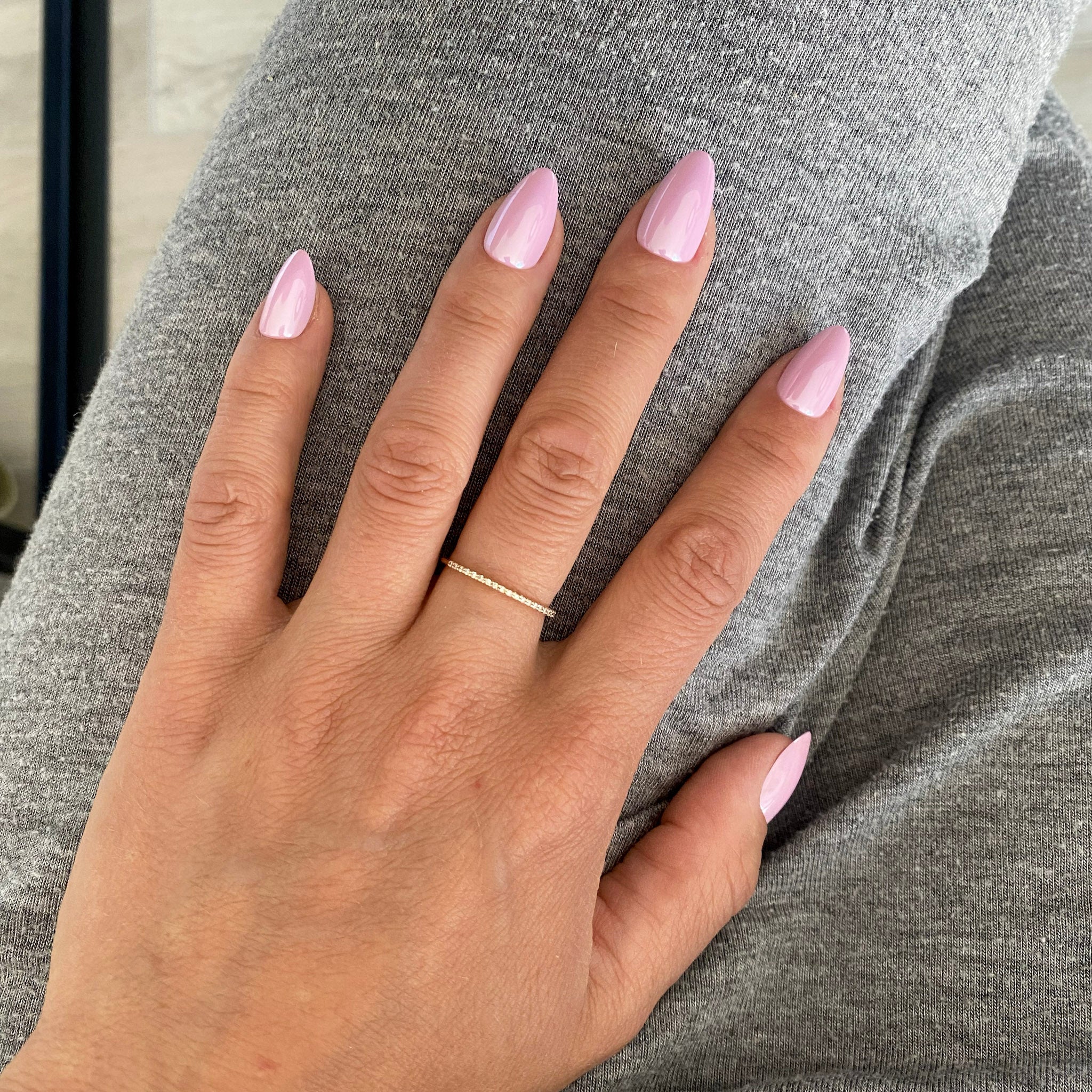 Press-on Nails Rose Orchidée amande courts portés sur main posée, bague fine dorée, pull gris doux, faux ongles rose nacré lumineux et féminins LYLY Nails