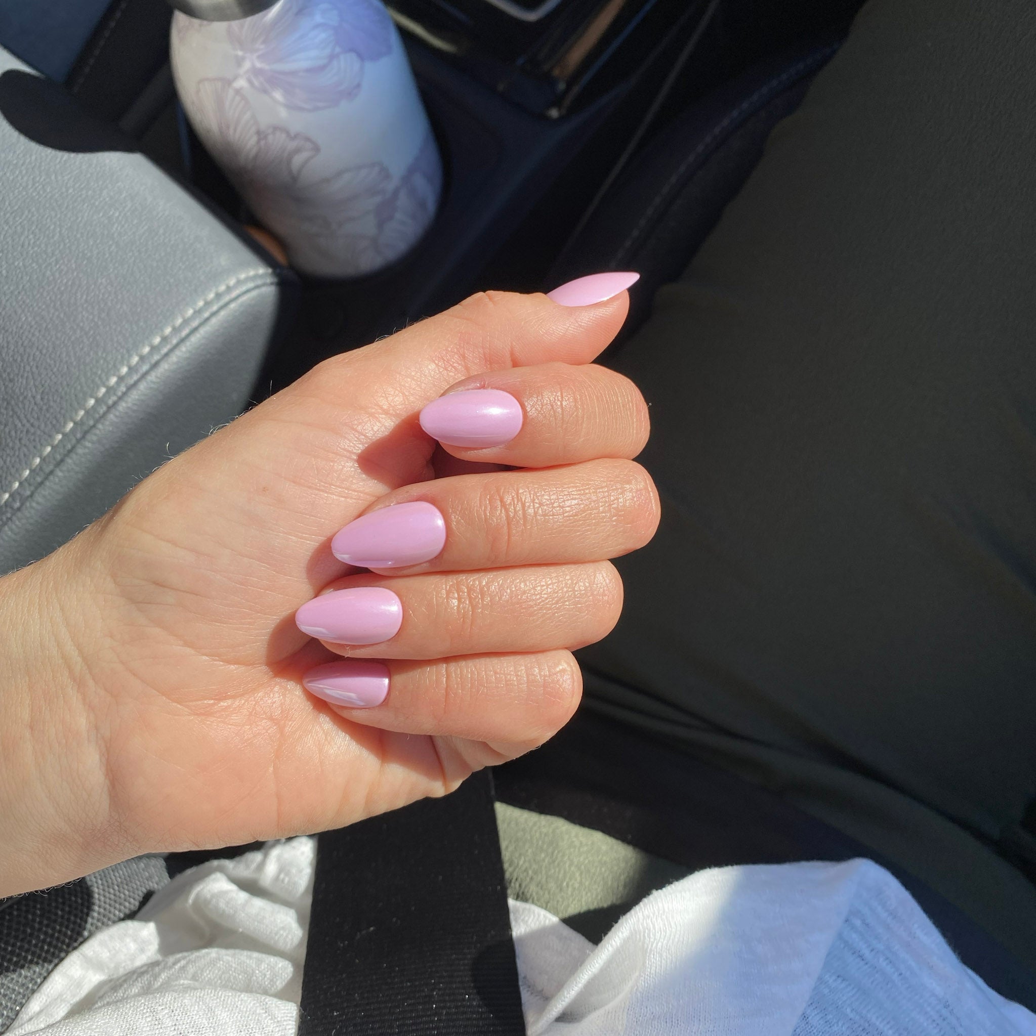 Faux ongles Rose Orchidée forme amande courte en voiture au soleil, ceinture noire et gourde florale, manucure rose tendre fraîche et élégante LYLY Nails